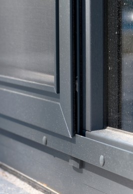 Zamknięta moskitiera przesuwna na drzwi balkonowe. Skrzydło z siatką wykonaną z włókna szklanego oraz uszczelkami szczotkowymi które gwarantują szczelność pomiędzy ramą moskitiery drzwiowej a ramą okienną poruszające się po szynie jezdnej (prowadnicy).