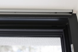 Antracytowa moskitiera przesuwna oraz antracytowa rama okienna widok od środka wnętrza.